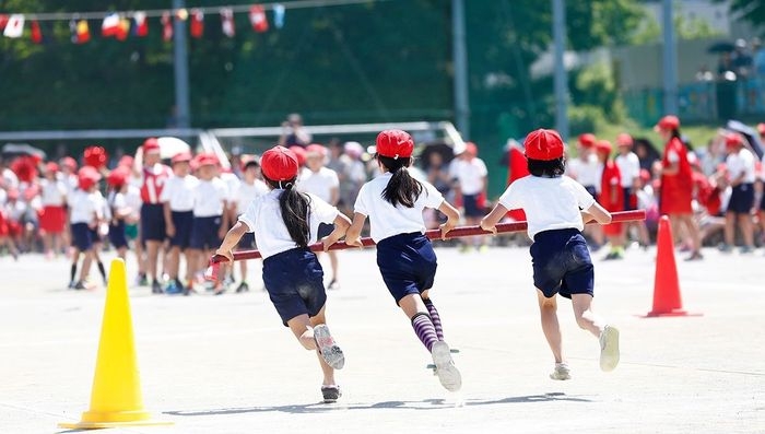 運動会でリレーのバトンを持って走る子どもたち